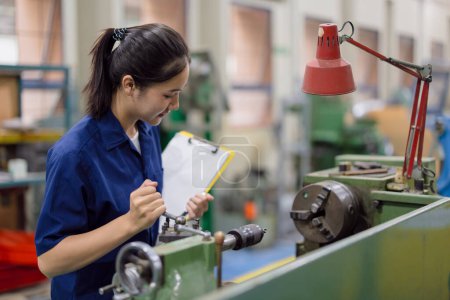 Trabajadora asiática trabaja en industria pesada con fresadora de torno CNC en fábrica de productos de acero