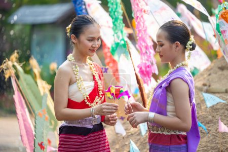Songkran festival. Northern Thai people in Traditional clothes dressing carrying sand into temple to build sand pagoda and decoration with colorful paper flag.