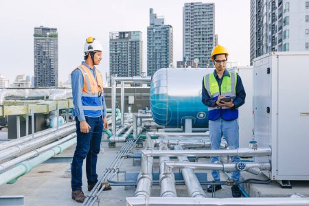 engineer teamwork technician workers service hotel boiler tank hot water supply pipe system. team working safety checking maintenance pipeline heating water delivery line at roof top outdoor.