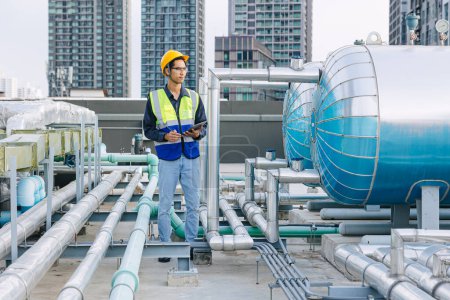 engineer male technician worker working service hotel boiler tank hot water supply pipe system. man safety checking maintenance pipeline heating water delivery line at roof top outdoor.