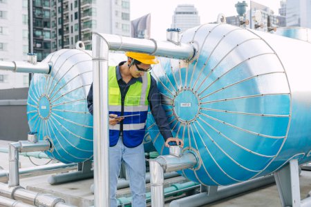 engineer male technician worker working service hotel boiler tank hot water supply pipe system. man safety checking maintenance pipeline heating water delivery line at roof top outdoor.