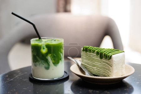 Foto de Productos de alimentos y bebidas dulces de té verde Matcha sirven en la cafetería, pastel de crepe verde y té verde con leche helada de cerca en la mesa. - Imagen libre de derechos