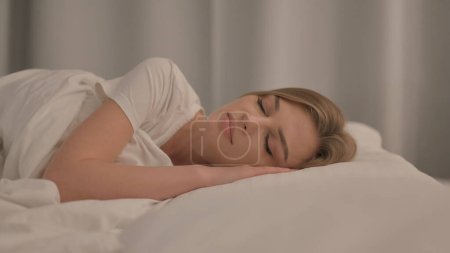 Foto de Vista lateral de la mujer joven durmiendo en la cama en casa - Imagen libre de derechos