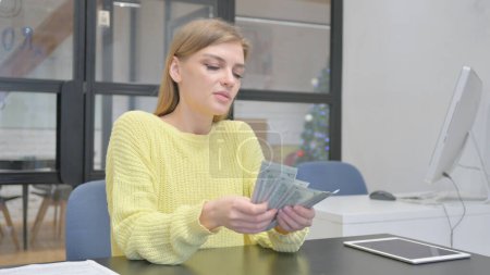 Jeune femme blonde compte l'argent au bureau