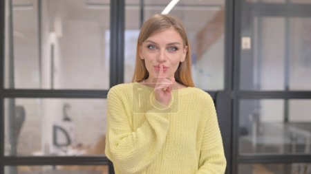 Téléchargez les photos : Portrait de jeune femme blonde avec doigt sur les lèvres, silence s'il vous plaît - en image libre de droit