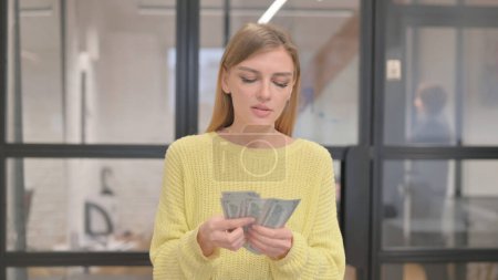 Portrait de jeune femme blonde comptant de l'argent