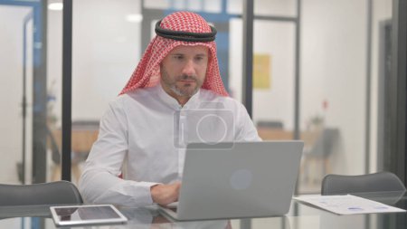 Hombre árabe trabajando en el ordenador portátil en la oficina
