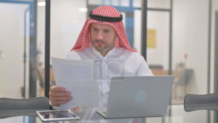 Hombre árabe trabajando en documentos en la oficina