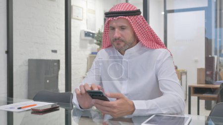 Middle Aged Muslim Man Working on Smartphone in Office