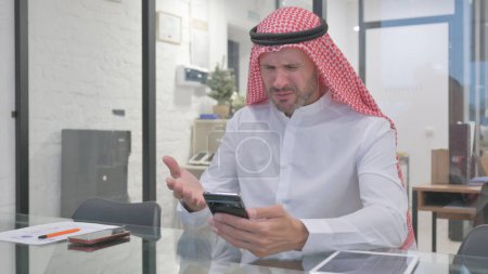 Middle Aged Muslim Man having Online Trading Loss on Phone