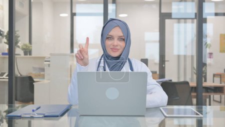 Médico en Hijab Agitar la cabeza en la negación mientras se trabaja en el ordenador portátil