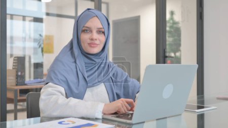 Mujer en Hijab sacudiendo la cabeza en la negación mientras trabaja en el ordenador portátil