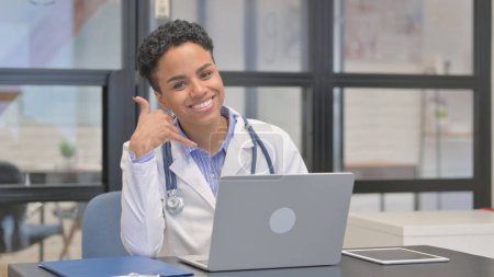 Nennen Sie mich Geste von Mixed Race Ärztin, während Sie Laptop verwenden