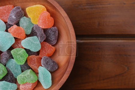 Téléchargez les photos : Un gros plan de bonbons gommeux de différentes couleurs et saveurs de fruits servis dans un bol en bois. - en image libre de droit