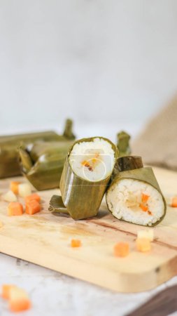 Téléchargez les photos : A close up of Lontong. Traditional food from Indonesia originating from rice filled with vegetables or meat and wrapped in banana leaves. Indonesian traditional food photo concept. - en image libre de droit