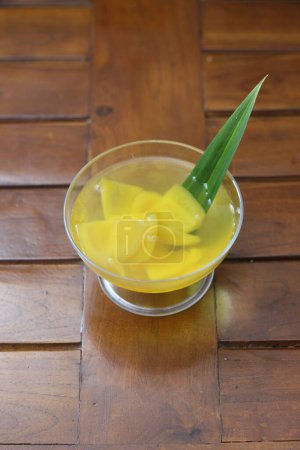 Photo for Glass of Candied Carica served fresh isolated on wood pattern background. Indonesian drinks and desserts. Carica or Manisan Carica. - Royalty Free Image