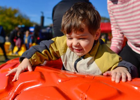 Foto de Lindo niño jugando dentro y sobre una rueda de tractor colorido en la feria de granja en Halloween - Imagen libre de derechos