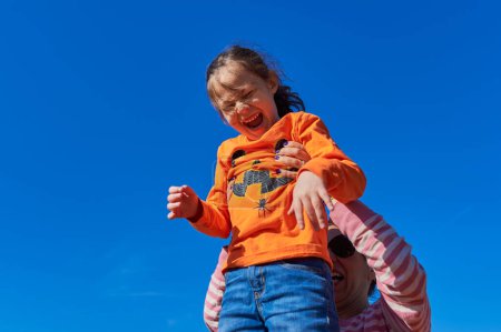 Foto de Bonita chica siendo sostenida en el aire por mamá contra un cielo azul - Imagen libre de derechos