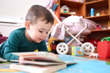 Photo for Young toddler boy looking at books and playing in his room - Royalty Free Image