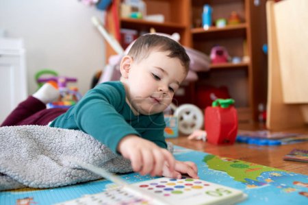 Photo for Young toddler boy looking at books and playing in his room - Royalty Free Image