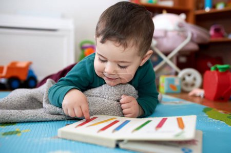 young toddler boy looking at books and playing in his room