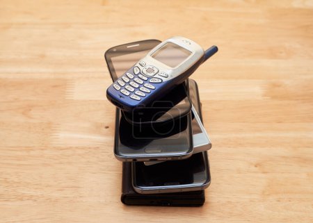 Téléchargez les photos : Un tas de vieux téléphones portables usés de différentes décennies empilés sur la table - en image libre de droit