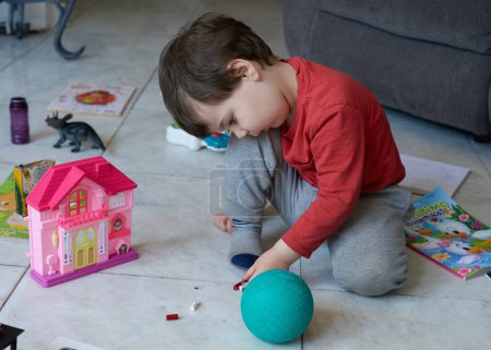 Téléchargez les photos : Mignon jeune garçon jouer avec des jouets dans le salon - en image libre de droit