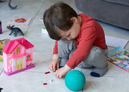 Téléchargez les photos : Mignon jeune garçon jouer avec des jouets dans le salon - en image libre de droit