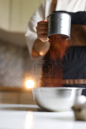 Photo for Confectioner prepares a cake, ingredients, cake preparation, step-by-step process, sifting cocoa through a sieve. High quality photo - Royalty Free Image