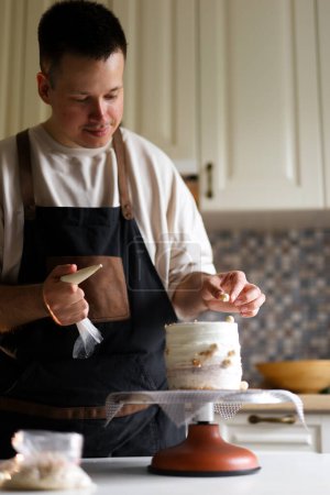 Téléchargez les photos : Sur cette photo, nous pouvons voir un pâtissier travailler à la création d'un magnifique gâteau. Ses mains manipulent habilement les ingrédients, leur donnant la forme et la texture nécessaires. - en image libre de droit