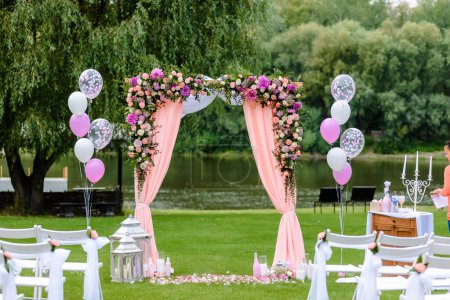 Photo for Outdoor ceremony, wedding arch with colorful flowers and balls on the background of the river and green grass. High quality photo - Royalty Free Image