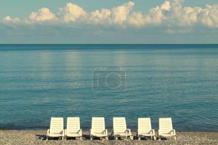 Chaises longues blanches au bord de la mer. Vacances en mer. Paysage marin.
