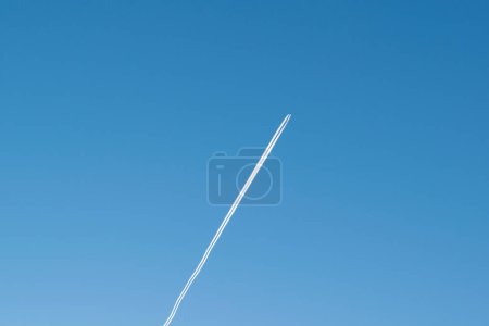 Trace blanche depuis un avion dans un ciel bleu clair. L'avion vole..