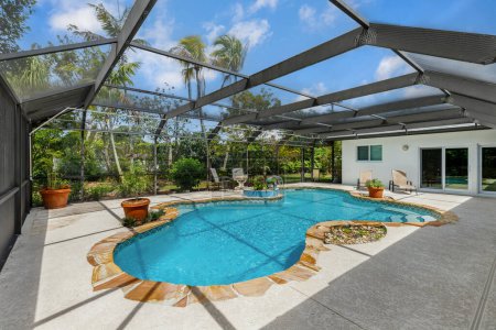 Téléchargez les photos : Belle piscine intérieure, dans la cour avec des plantes en pot, chaises bleues, arbres, clôture privée, sol carrelage - en image libre de droit