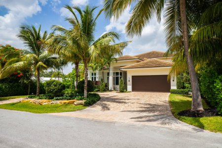 Téléchargez les photos : Façade d'un bel endroit, avec un jardin devant composé de palmiers, herbe courte et plantes tropicales, à Coral Ridge à Miami, allée, trottoir et rue - en image libre de droit