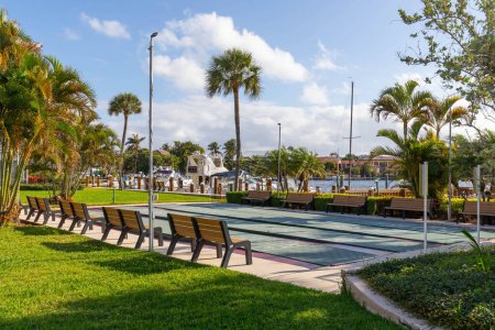 Photo for Shuffleboard courts, benches around, with palm trees blue sky and boats in the background - Royalty Free Image