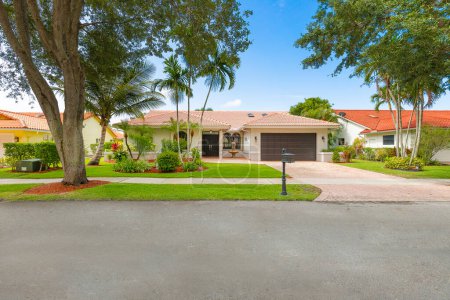 Foto de Fachada de condominio en Boca Raton, Miami, jardines tropicales, césped corto, acera, calle, tejado de azulejos, cielo azul - Imagen libre de derechos