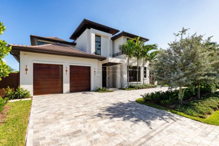 Photo for Mansion facade in Harbor Beach neighborhood in Fort Lauderdale, driveway and walkway to front door, short grass, trees, palms, windows, blue sky - Royalty Free Image