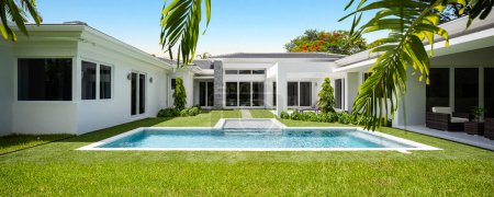 Backyard of elegant and modern house, located in Glenvar Heights, in Miami-Dade, white walls, black tiles, glass doors, short cepes, T-shaped pool, trees and palm trees around, sun loungers, blue sky in the background