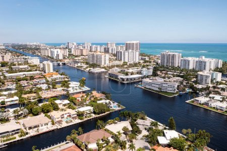 Téléchargez les photos : Vue aérienne par drone du quartier de Coral Ridge, à Fort Lauderdale, Miami, États-Unis, zone commerciale, avec canaux et bateaux naviguant, maisons et demeures de luxe, végétation tropicale abondante autour, ciel bleu - en image libre de droit