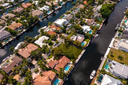Téléchargez les photos : Photoshoot Footage of Aerial Drone view in Florida, Usa, mettant en valeur l'horizon avec plusieurs bâtiments dans un canal d'eau entouré d'une végétation abondante un ciel bleu parfait. - en image libre de droit