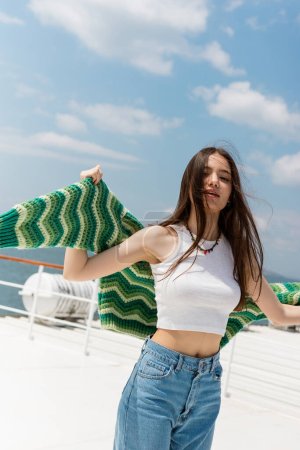 Portrait of brunette woman holding sweater during cruise on ferry boat in Turkey 