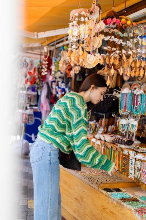 Photo for Side view of young woman choosing accessories on flea market in Turkey - Royalty Free Image