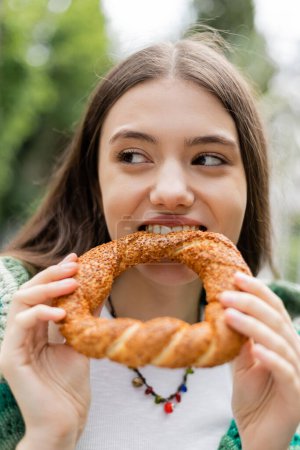 Mujer joven mordiendo pan turco simit al aire libre en Estambul