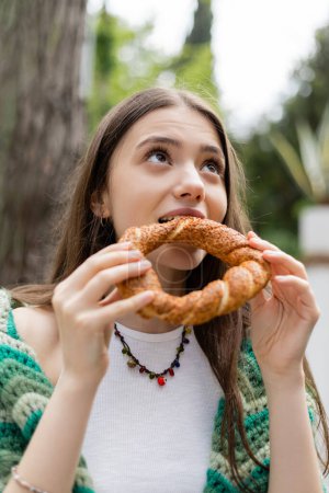 Brunette woman eating traditional turkish simit bread in Istanbul