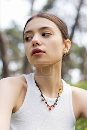 Téléchargez les photos : Vue à angle bas de la jeune femme en haut et collier regardant loin à l'extérieur - en image libre de droit