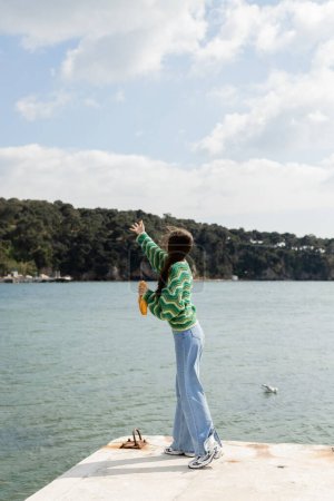 Junge Frau in stylischem Outfit mit Brot auf Pier in Istanbul