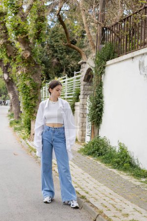 Stylish brunette woman in shirt and jeans standing on urban street in Istanbul
