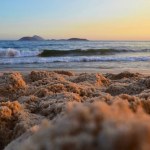 Beach sand close-up at sunset in Rio de Janeiro. View of sand on a beach in Rio de Janeiro with the beautiful sea in the background