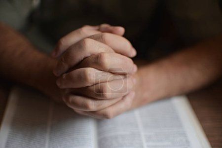 primer plano en las manos de una persona irreconocible leyendo la Biblia y orando.